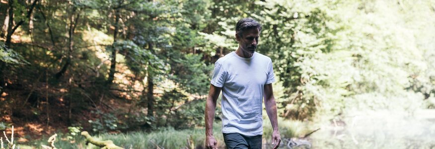 Mann balanciert auf Stamm neben See im Wald